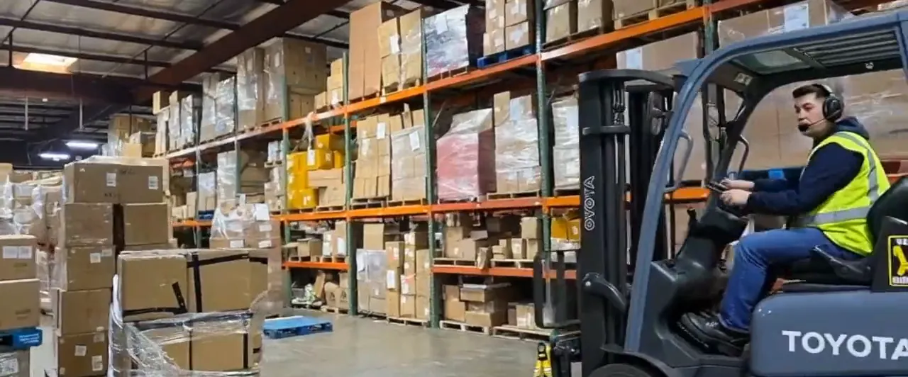 A forklift moving inventory down a warehouse aisle